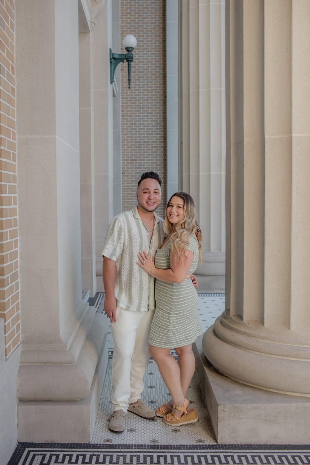 Kallie and Alejandro standing together between tall stone columns