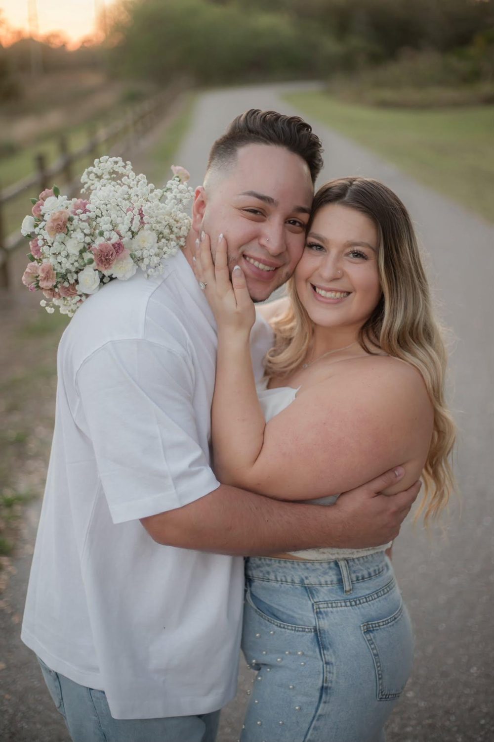 Kallie and Alejandro smiling cheek to cheek with a bouquet of blush flowers