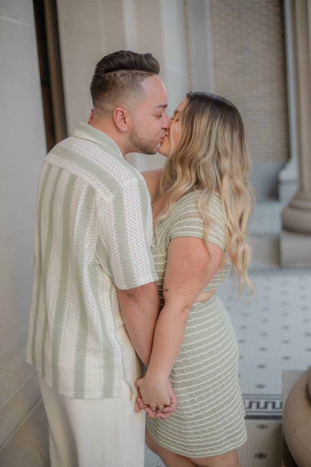 Alejandro kissing Kallie beneath a stone colonnade